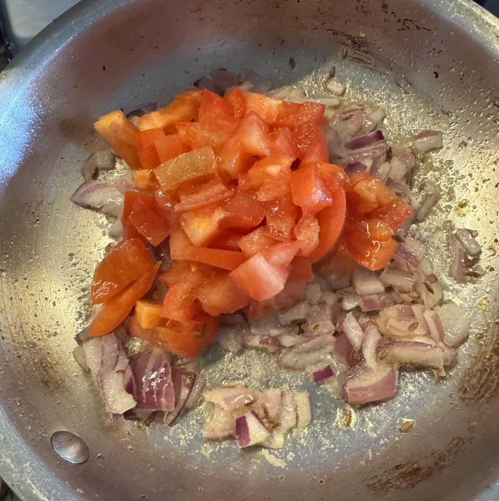 Fresh tomatoes added to sautéed onions