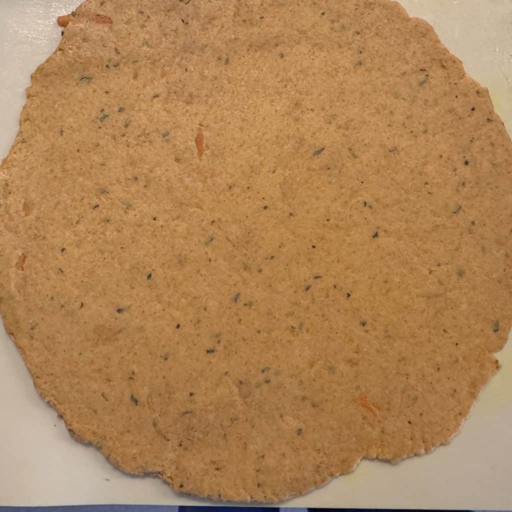 Evenly rolled rajgira paratha on parchment paper, ready to be cooked using light pressure with a thin rolling pin.