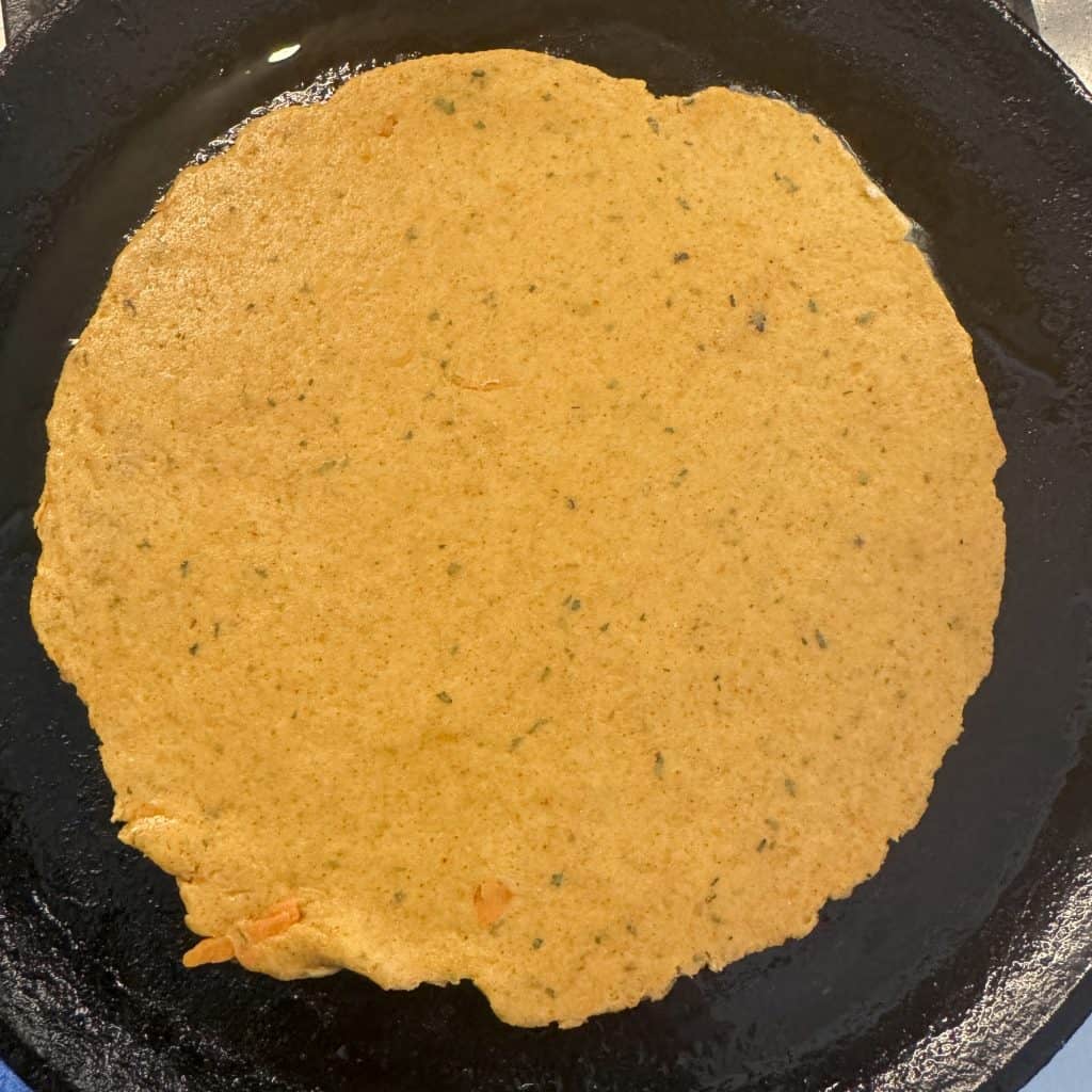 Raw paratha on a hot tawa, cooking on medium heat with light oil.